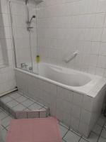 a bathroom with a bath tub and a pink stool at Confortable appart 5 mins centre de valenciennes in Anzin
