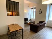 a living room with a leather couch and a table at Le Descartes: cosy in the city centre in Poitiers