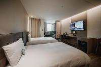 a hotel room with two beds and a desk and a television at Hub Hotel Kaohsiung Yawan Branch in Kaohsiung