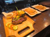 锡基霍尔U Story Resort的砧板上放着一块牛排，旁边还有蔬菜和面包。