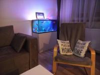 a living room with a fish tank and a chair with two pillows at TOP Apartman in Šabac