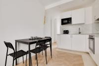 a white kitchen with a black table and chairs at Appartement Bercy in Paris