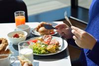 東京にあるハイアット ハウス 東京 渋谷の食べ物の皿を持ってテーブルに座っている女性