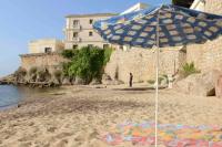a blue and white umbrella on a sandy beach at Studio golfe-juan piscine plage privée tennis in Vallauris