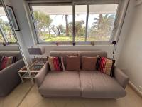 a couch with pillows sitting in a room with a window at Studio golfe-juan piscine plage privée tennis in Vallauris