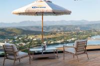 Duas cadeiras e uma mesa com um guarda-sol no deque em The Ivory Haus em Plettenberg Bay