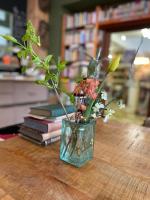 un vase avec des fleurs assis sur une table avec des livres dans l&#39;établissement La Reduiste, à Redu
