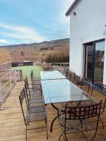 a table and chairs on a deck with a tennis court at Le Loft in Stoumont