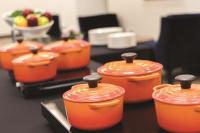 a group of orange pots on a table with a bowl of fruit at Hyatt Place Chicago O'Hare Airport in Rosemont