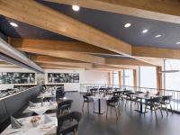 un restaurante con mesas y sillas blancas y techos de madera en Das Neue CAPITOL, en Bad Berleburg