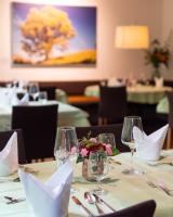 a table in a restaurant with wine glasses and flowers at Gesundhotel Bad Reuthe in Vorderreuthe