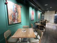 a restaurant with tables and chairs and a painting on the wall at Greenside Apartment 1 in Pristina