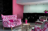 une chambre avec un canapé rose et deux chaises dans l&#39;établissement Citadines City Centre Lille, à Lille