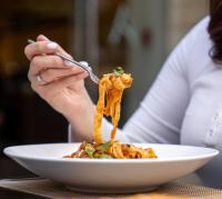 a woman eating a plate of pasta with a fork at The Abdali Boulevard Hotel in Amman
