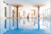 a woman sitting in the water in a swimming pool at 6717 Nature Hôtel &amp; Spa Le Clos des Délices in Ottrott