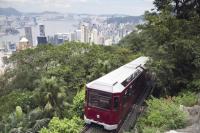 a red and white train on a hill with a city at Four Seasons Hotel Hong Kong in Hong Kong