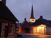 a church with a steeple and a street with buildings at LE CAMELIA in Saint-Viâtre