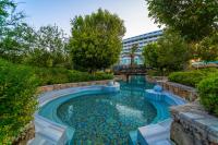 a swimming pool in a garden with a building in the background at Concorde De Luxe Resort - Prive Ultra All Inclusive in Lara