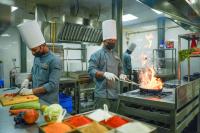 two chefs preparing food in a commercial kitchen at Vyna Hillock Resort in Vythiri