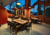 a restaurant with tables and chairs and large windows at Vyna Hillock Resort in Vythiri