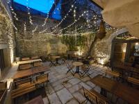 een patio met houten tafels, stoelen en verlichting bij LE PATIO in Grignan