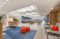 a lobby with orange chairs and tables in a building at Hilton Irvine/Orange County Airport in Irvine