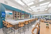 a restaurant with a long bar with chairs and tables at Hilton Irvine/Orange County Airport in Irvine