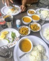 Una mesa con platos de comida y tazones de sopa y arroz. en Triyugi Heights cottage sitapur, en Trijugi Nārāyan