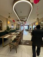 Un hombre de pie en una habitación con mesas y sillas. en Hotel Tamarind Tree, en Kharar