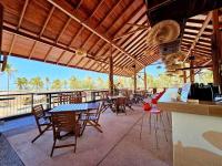 ein Restaurant mit Tischen und Stühlen und Blick auf das Meer in der Unterkunft Borneo Beach & Mangrove Resort in Tuaran