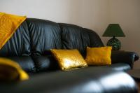 a black leather couch with gold pillows on it at 100 m2 entre Angers et saumur proche châteaux in Saint-Clément-des-Levées
