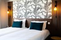 a bedroom with a bed with two blue pillows at Hôtel Mar I Cel &amp; Spa in Canet-en-Roussillon