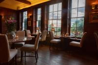 a dining room with tables and chairs and windows at Burleigh Court Hotel in Stroud