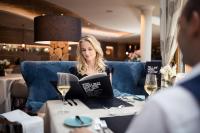 a woman sitting at a table with a laptop at Hotel Chalet Das Alpenschlössel in Saltusio