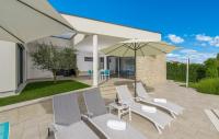 a group of chairs and an umbrella on a patio at Contemporary Villa Nada with Pool and Sauna in Tinjan