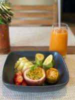 a plate of food with fruit and a glass of orange juice at BLUE VELVET in Nosy Be