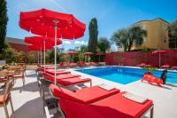 a pool with red chairs and umbrellas next to a pool at Hotel Carlton in Beaulieu-sur-Mer