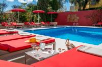 a pool with red tables and chairs next to a swimming pool at Hotel Carlton in Beaulieu-sur-Mer