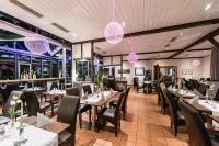 un restaurante con mesas, sillas y luces rosas en Landhotel Burg im Spreewald - Resort & Spa, en Burg