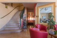 a lobby with a staircase and a red chair at Hotel Bristol in Chalons en Champagne