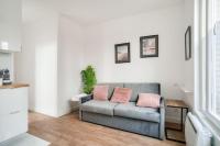 a living room with a couch with two pink pillows at Studette 4 calme et Lumineux, entièrement équipée in Créteil