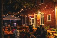 un grupo de personas sentadas en mesas fuera de un edificio en Auberge de Jeunesse des Balcons, en Baie-Saint-Paul