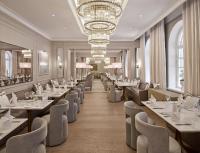 um restaurante com mesas e cadeiras e um lustre em Waldorf Astoria Helsinki em Helsínquia