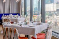 a dining room with white tables and chairs and windows at Warsaw Presidential Hotel in Warsaw