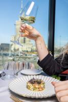 a person holding a wine glass over a plate of food at Warsaw Presidential Hotel in Warsaw