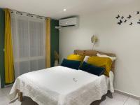 Schlafzimmer mit einem Bett mit gelben und blauen Kissen in der Unterkunft Myosotis, charmant logement central avec piscine privée, wifi et parking gratuit in Petit-Bourg