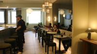a man standing in a restaurant with people sitting at tables at Gspot Hostels & Love Triangles Pizzeria in Lisbon