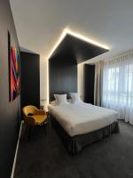 Un dormitorio con una cama grande y una silla amarilla. en LOGIS Hôtel Borel, en Dunkerque