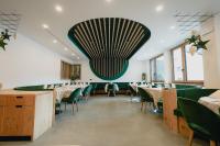 Un comedor con sillas verdes y un gran techo. en Olimpionico Hotel, en Castello di Fiemme