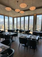 Un restaurante con mesas y sillas y grandes ventanales. en Sky Hotel Tirana, en Tirana